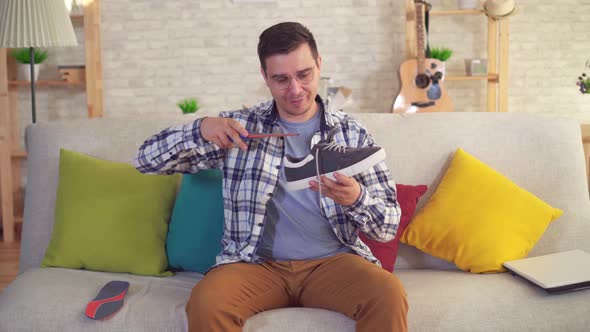 Man Sitting on the Couch Inserts Orthopedic Insoles in Shoes