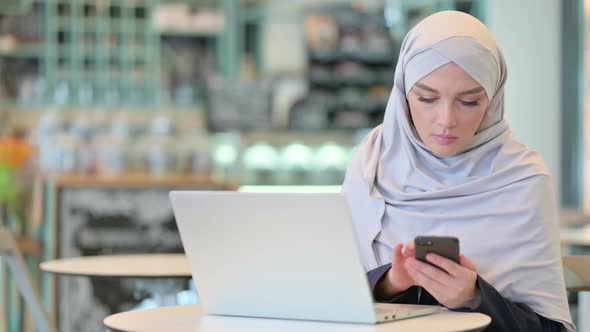 Arab Woman Working on Smartphone and Laptop