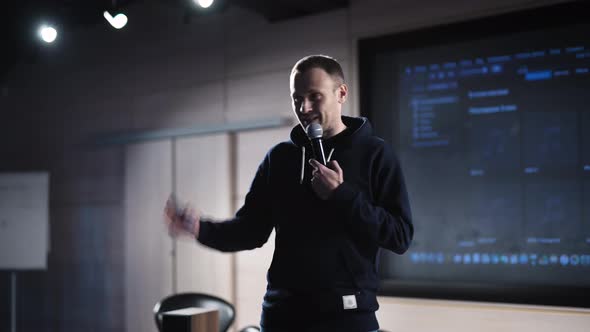 A Young Charismatic Man Makes a Presentation in a Dark Auditorium