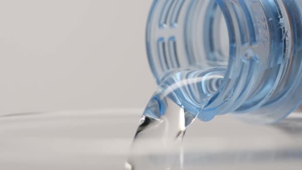 Pouring of clear water from a plastic bottle in a glass