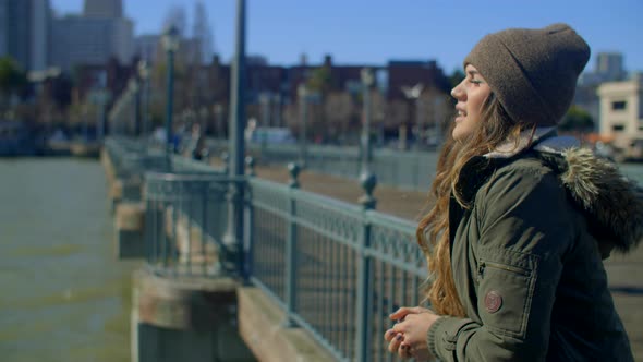 thoughtful young woman looks across water from pier and considers future