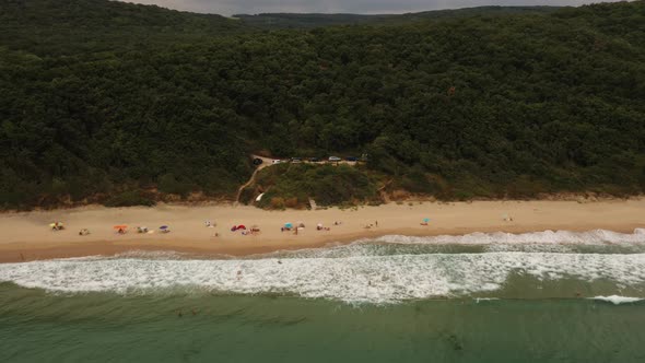 Aerial Drone Top View Over Ocean Sea White Sand Beach Rocky Mountains Cliffs and Dense Forest Bright