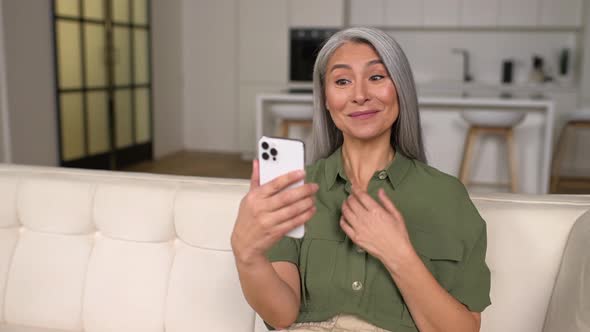 Happy Smiling Mature Woman Sitting at the Living Room Relaxing and Talking Via Video Connection