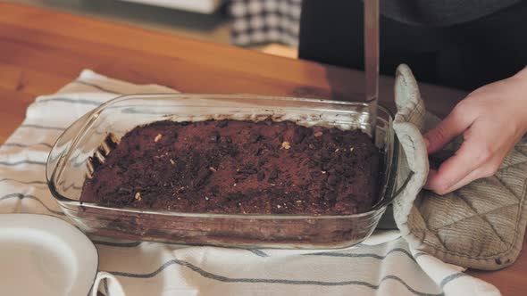 Slow motion shot of woman cutting chocolate cake in baking tray