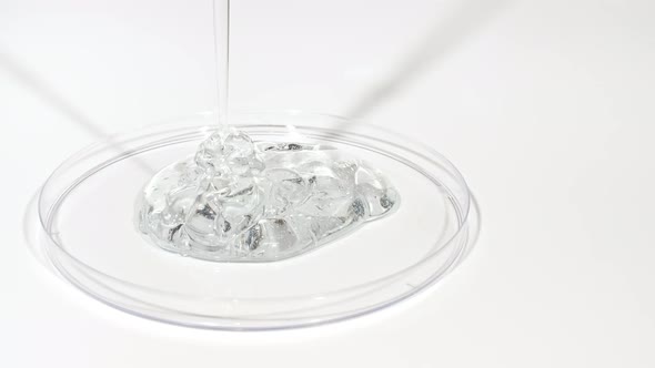 Transparent Cosmetic Gel Fluid Dripping Into the Glass Bowl of Petri