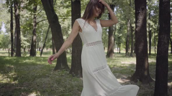 Adorable Young Girl Dressed in a White Long Summer Dress Spin in the Park. Leisure of a Pretty Woman