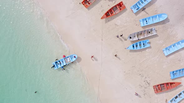 Group tourist entering boat on sea shore for boat ride trip on Caribbean Sea - Drone top down shot