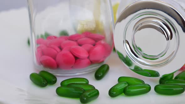 Rotating shot of colorful tablets in glass bottles and green tablets around