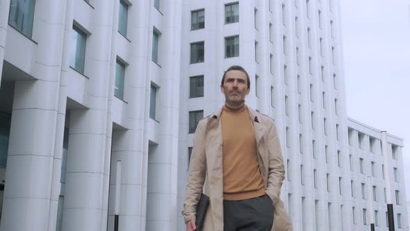 Front view of an ambitious handsome businessman walking down a city street in the city center.