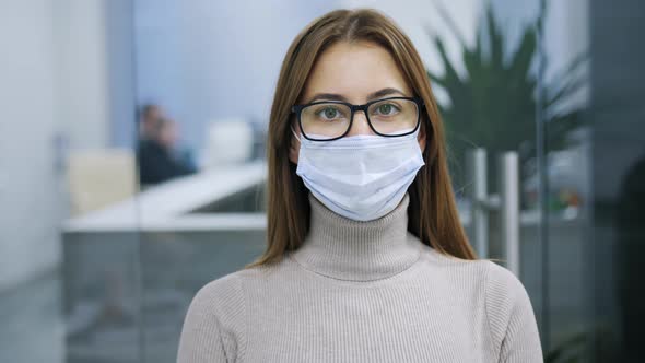 Portrait of a Woman in Glasses and a Protective Mask Looking Into the Camera Office Worker