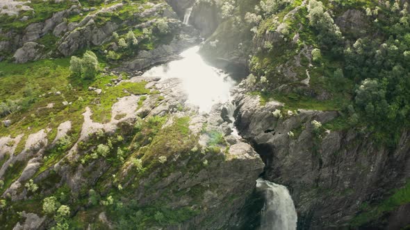 Drone Over Waterfall Cascading Down Into Rocky Valley