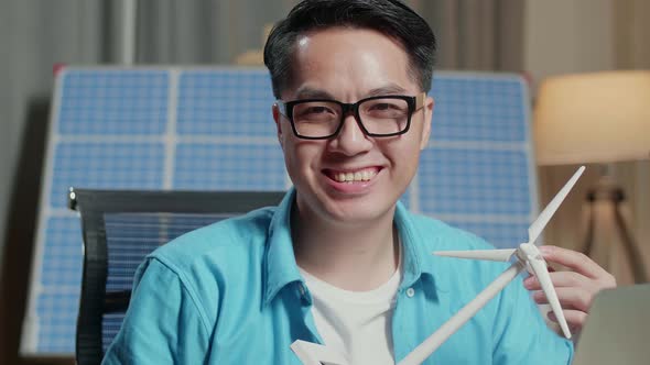 Close Up Of Asian Man Look At Wind Turbine And Smile To Camera While Working With Laptop