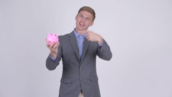 Happy Young Businessman Holding Piggy Bank and Giving Thumbs Up