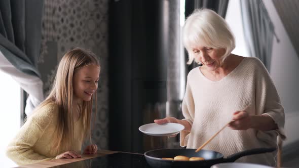 Woman preparing cheese cakes and talking with granddaughter