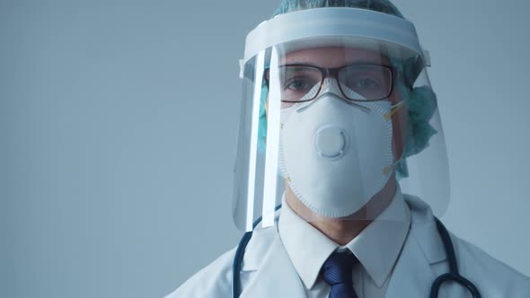 Studio portrait of young professional medical doctor in mask, hat and protective visor.