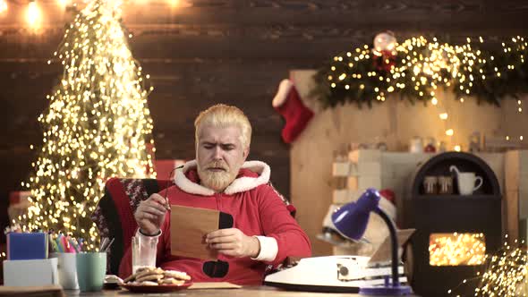 Santa Claus Sitting at Home and Writing on Paper To Do List with Quill Pen and Ink at Night