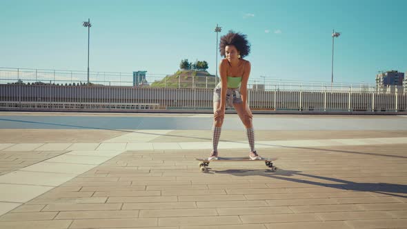 Beautiful young woman cruising around the city with her longboard.