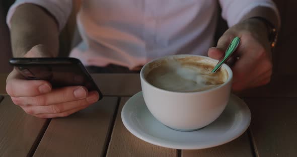 Unrecognizable Businessman Using Phone While Drinking Coffee