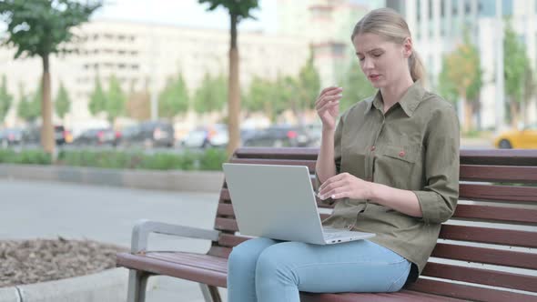 Distressed Woman with Headache Using Laptop while Sitting Outdoor on Bench