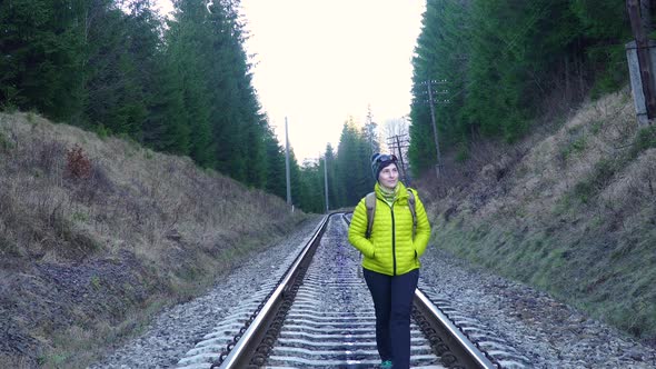 A Woman with a Backpack Walks on the Railway