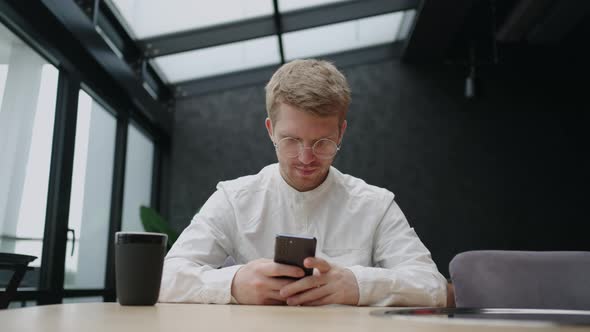 Businessman in Lunch in Cafe Sitting at Table and Using Smartphone Reading News in Internet Viewing