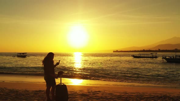 Young happy lady travelling having fun on the beach on clean white sand and blue 4K background