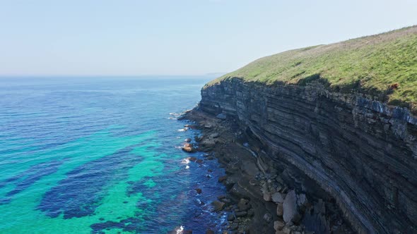 Large rocky cliffs stratified on turquoise sea water shore of northern Spain