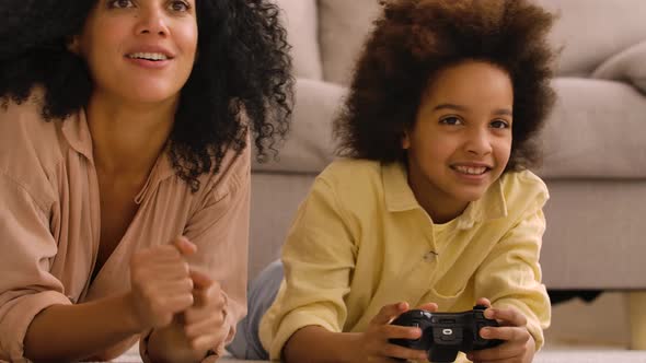 Little African American Girl Plays Game on Wireless Joystick and Rejoices Victory