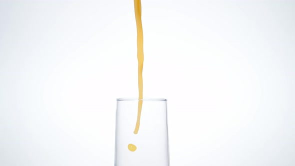 Camera follows pouring orange juice into glass. Slow Motion.