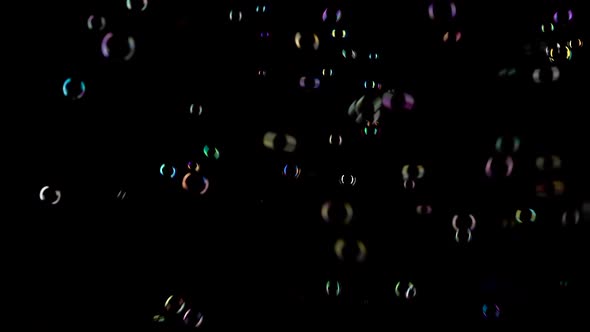 Small Round Transparent Soap Bubbles Fly Very Fast. Black Background