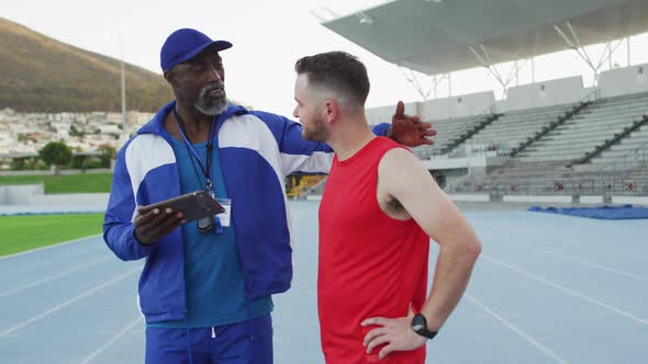 African american male coach and caucasian athlete talking during training session