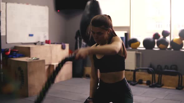 Strong Sportive Brunette Girl in Her 20's Performing Battle Ropes Workout at the Gym