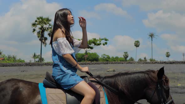 Cute Chinese Teenager Rides a Horse On The Beach In Bali