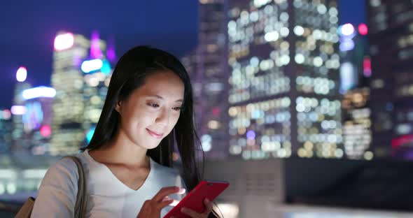 Woman use of mobile phone in city at night