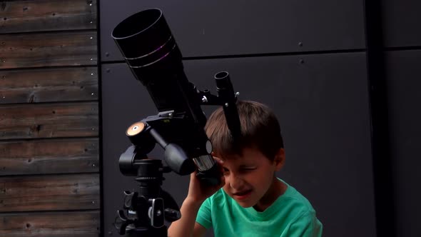 Little Tanned Boy is Setting Up a Telescope on a Summer Day to Look at the Sky