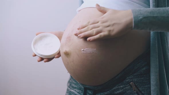 Pregnant Lady Applies Moisturizing Lotion on Tummy Closeup