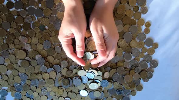 Person Two Hands Rakes Coins on Table and Pours Spills From Handful to Surface