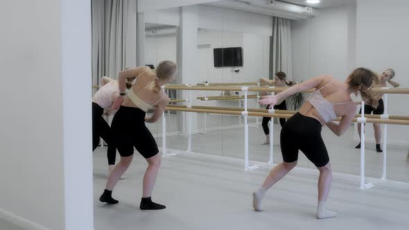 Three young girls dance in a white bright studio in front of a mirror. Slow motion, smooth motion.