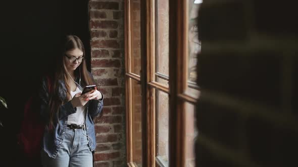 Attractive Girl Standing By Window and Texting 