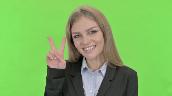 Cheerful Businesswoman Showing Victory Sign Against Chroma Key
