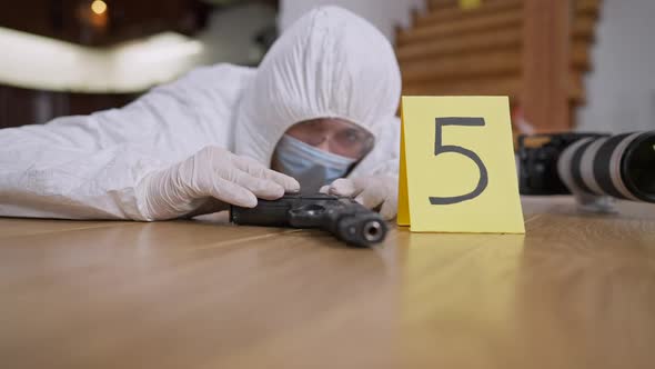 Weapon Lying on Floor with Blurred Forensic Scientist Examining Evidence