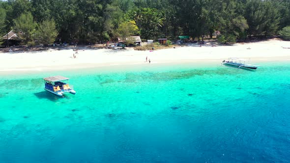 Touring boat anchoring on calm clear water of blue azure lagoon washing white sandy beach of tropica