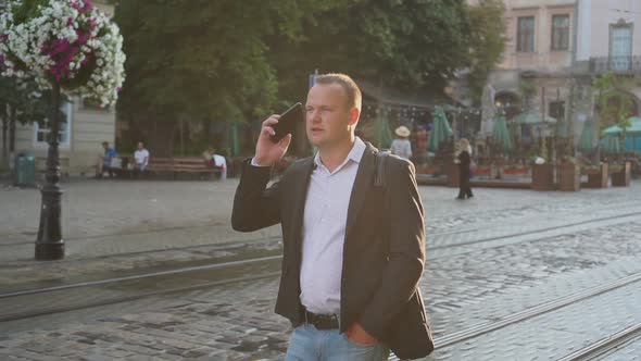 Caucasian Businessman Walking of the Street at the Ancient City Center and Talking on the Phone