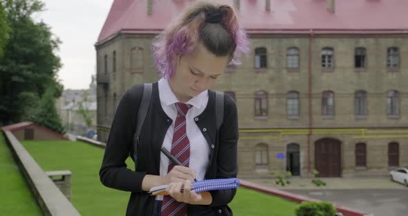 Teenager Girl in School Uniform with Backpack Writing and Showing Word Start