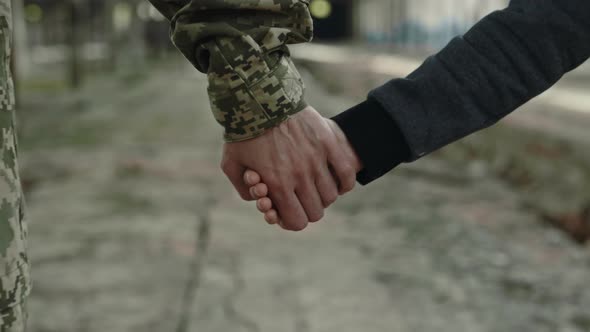 Son and Military Mother Holding Hands Among Old Plant