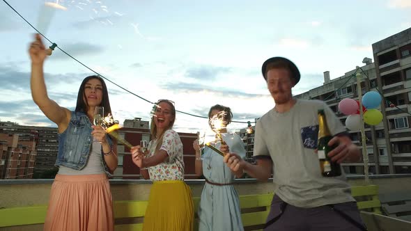 Friends having fun dancing and playing with firework candles