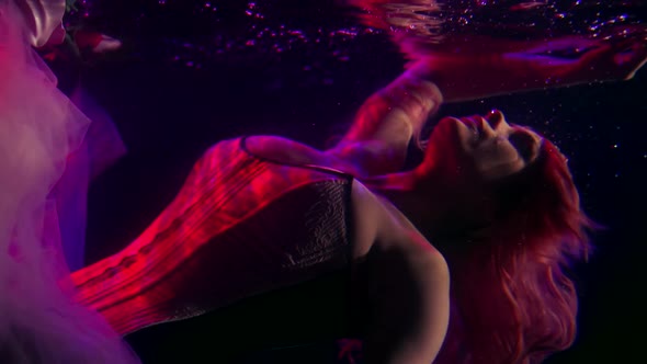 a Woman with Long Hair and a Corset Hovers Horizontally Under the Surface of the Dark Water and