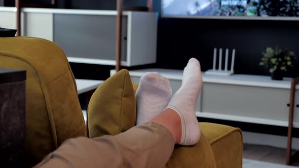 Legs in White Socks Lie in Front of the TV.