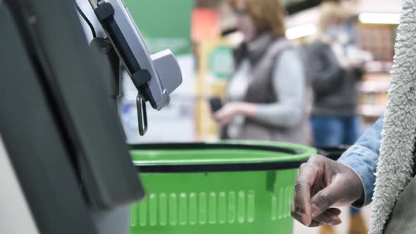 African Man Makes Purchases at a Selfservice Checkout in a Supermarket with a Closeup Finger