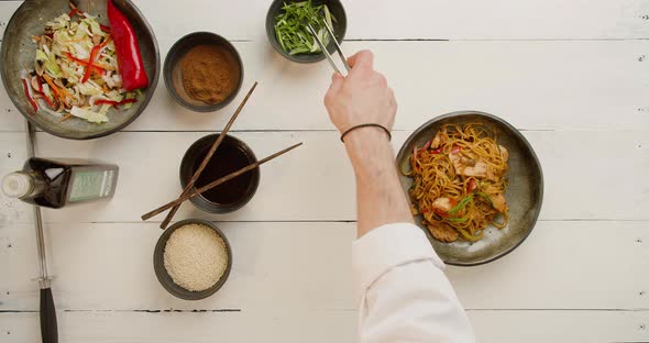 The Cook Sprinkles Onions and Sesame Seeds on Top of Food Chinese Noodles